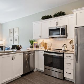 A modern kitchen featuring stainless steel appliances and white cabinetry.