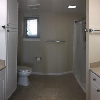 A modern bathroom with a toilet, sink, shower, and window.