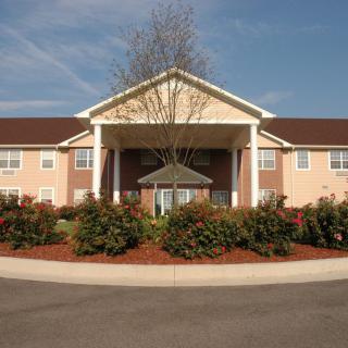 A residential building with a landscaped entrance under a clear blue sky.