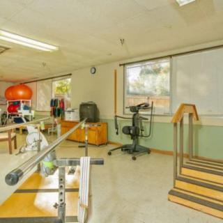 An empty rehabilitation room equipped with various exercise and therapy equipment.