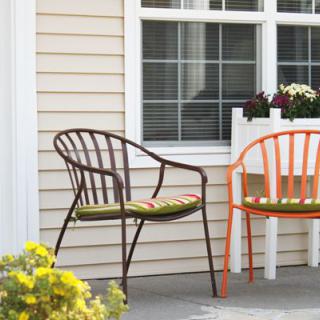 Two colorful chairs on a patio next to a window with plants.
