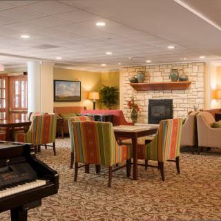 A cozy lounge area with comfortable seating and a piano near a fireplace.