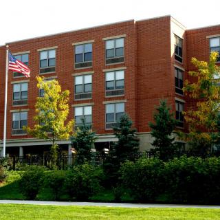 A brick building with an American flag and landscaped surroundings.