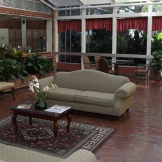 A cozy lobby area with a sofa and coffee table surrounded by large windows and plants.