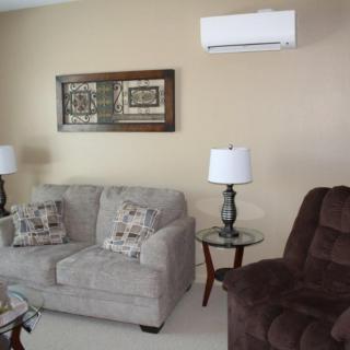 A cozy living room with a sofa, armchair, and decorative lamps, featuring neutral tones and wall art.
