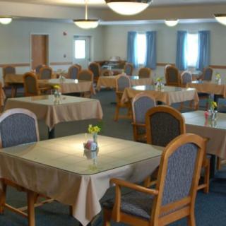 A spacious dining area with multiple tables and chairs, each table adorned with a small vase of flowers.