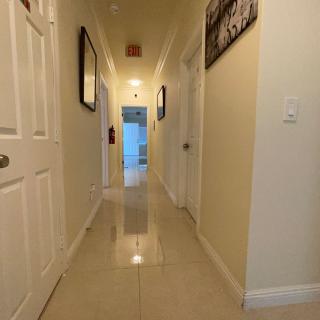 A well-lit hallway in a home featuring artwork and several doors.