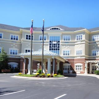 A modern building with multiple flags at the entrance and a spacious parking area.