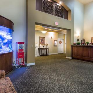 A welcoming lobby with a reception desk and a large fish tank, featuring cozy lighting and decorative elements.