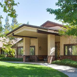 A modern residential house with a well-maintained lawn and surrounding trees.