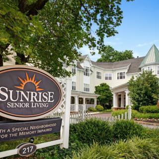 Entrance to Sunrise Senior Living with a welcoming sign and garden.