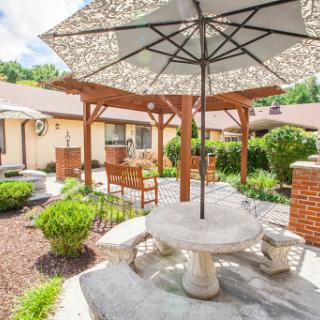 A serene outdoor garden space featuring a stone table and umbrella, perfect for relaxation.