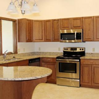 A modern kitchen with granite countertops, stainless steel appliances, and wood cabinets.