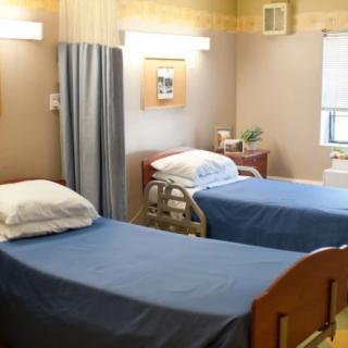 A hospital room with two neatly made beds and medical equipment.