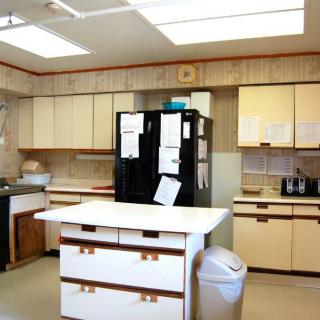 A vintage-style kitchen with cream-colored cabinets, a black refrigerator covered in notes, and an island countertop.