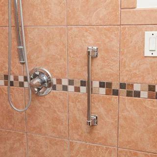A bathroom shower area with a grab bar installed on tiled walls for safety.
