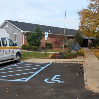 A view of a building with a designated handicapped parking space and an accessible van parked nearby.