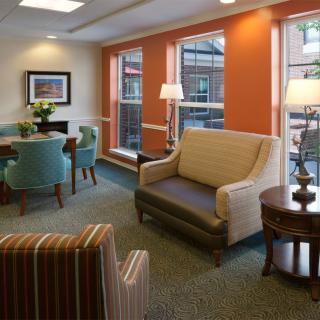 A cozy living room with comfortable seating, large windows, and warm lighting.