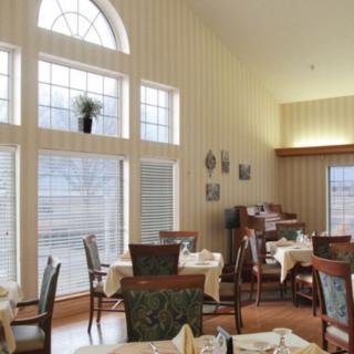 A well-lit dining room with large windows, tables, and chairs arranged neatly.