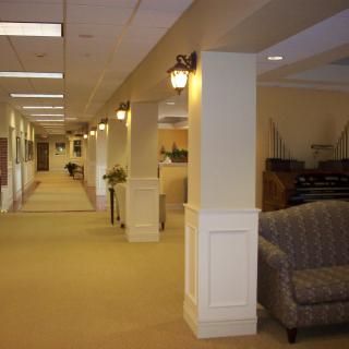 A well-lit office hallway with carpeted flooring and comfortable seating.