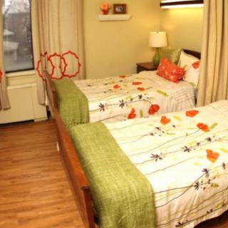 A cozy bedroom with twin beds, floral bedding, and warm lighting.