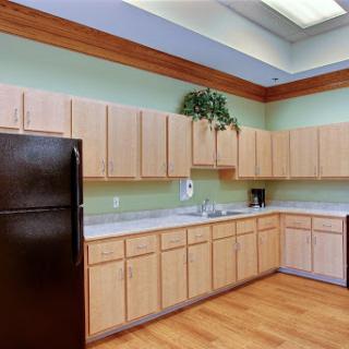 A modern kitchen featuring wooden cabinets and green walls, equipped with essential appliances.