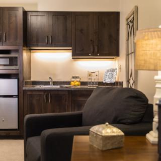 A modern kitchen and living area showcasing a cozy interior with dark wood cabinets and ambient lighting.