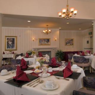 An elegant dining room setup with tables adorned with red napkins and decorative place settings.