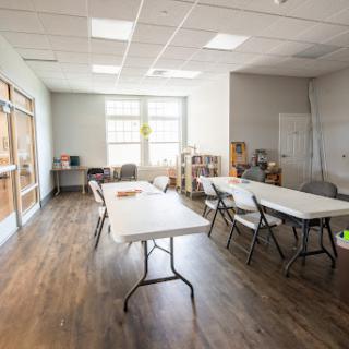 A spacious and bright room featuring several tables and chairs, suitable for meetings or classes.