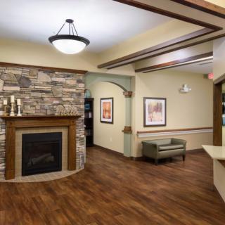 A modern lobby area with a stone fireplace and wooden flooring.