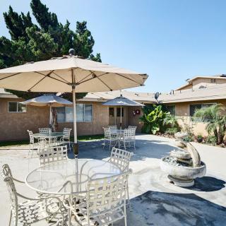 A sunny outdoor patio area with tables, chairs, and umbrellas.