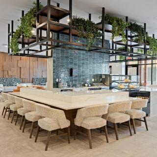 A modern kitchen with an island and open shelving adorned with greenery.