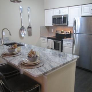 A modern kitchen with stainless steel appliances and a marble countertop.