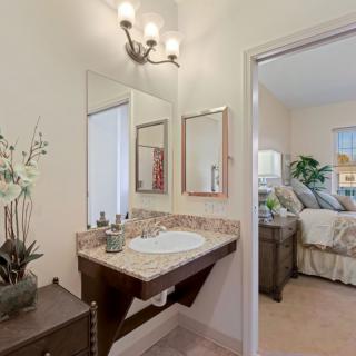 A cozy bathroom with a sink and mirror adjacent to a bedroom.