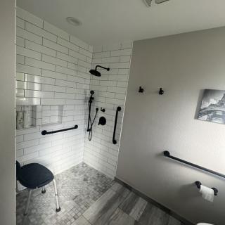 A modern, accessible bathroom with a walk-in shower, featuring grab bars and a shower seat.