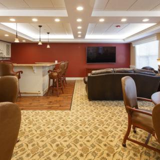 A cozy living room with a bar counter, comfortable seating, and a large television.
