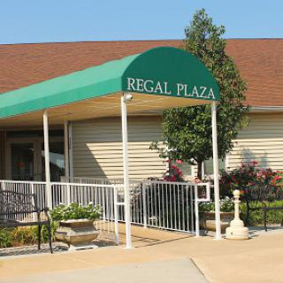 The entrance of Regal Plaza, featuring a green canopy and well-maintained landscaping.