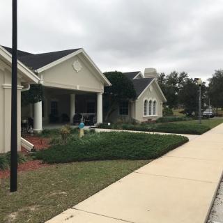 A suburban area featuring a building with a landscaped garden and a sidewalk on a cloudy day.