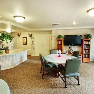 A cozy living and dining area with a TV, bookshelves, and indoor plants.