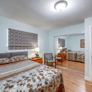 A cozy bedroom with a bed, mirrored closet doors, and a wooden floor.