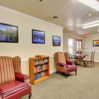 A cozy living room with comfortable chairs, a bookshelf, and wall artwork.