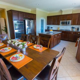 A modern kitchen and dining area featuring wooden cabinets, a central island, and a table set for dining.
