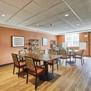 A well-lit dining area with wooden tables and chairs, adorned with artwork on the walls.