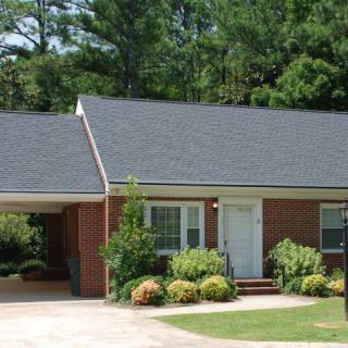 A brick house with a carport and a well-maintained front yard.