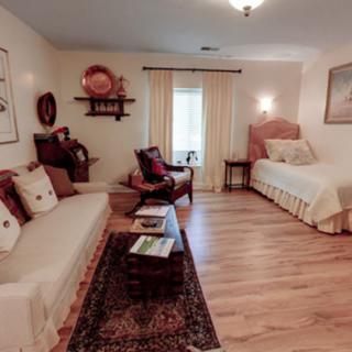 A cozy living room with warm decor, featuring a sofa, a bed, and wooden flooring.
