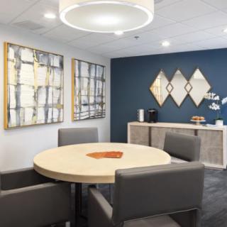 A modern office meeting room with a round table and abstract art on the walls.