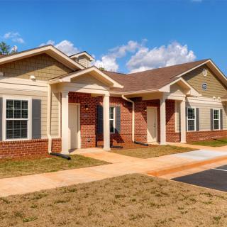 A suburban residential house with a brick facade and well-kept exterior under a clear blue sky.