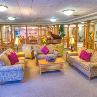 A cozy lounge area with comfortable seating, a piano, and warm lighting.