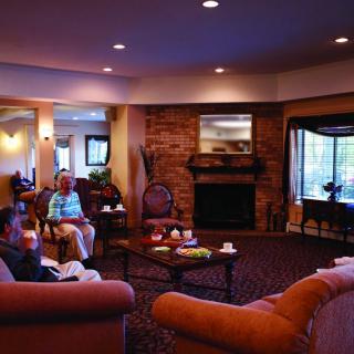 A cozy living room with a fireplace and people relaxing on couches.
