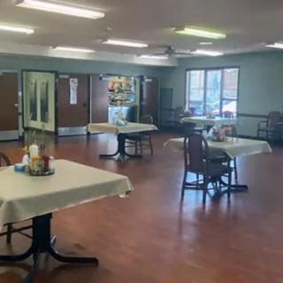 An empty dining room with arranged tables and chairs, ready for service.